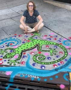 Susan Newman Lerer sitting by lizard art for drain by Swati Rostogi